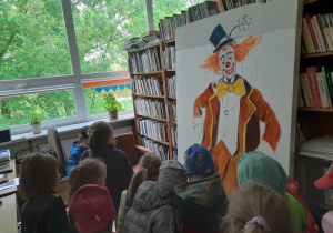 Przedszkolaki podziwiają duży obraz przedstawiający klauna.