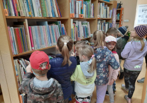 Grupa dzieci ogląda półki z książkami.