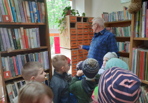 Pan bibliotekarz prezentuje dzieciom katalog książek.
