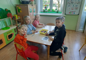 Pięcioro dzieci przy stoliku koloruje flagi państw należących do UE.