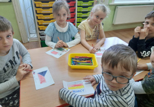 Dzieci przy stoliku kolorują flagi państw należących do UE.