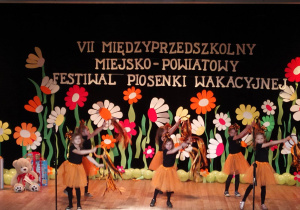 Grupa dziewczynek z ozdobami ze wstążek podczas tańca.
