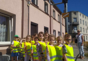 Grupa przedszkolaków przy sygnalizatorze świetlnym oczekuje na zielone swiatło.