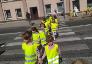 Dzieci przy palącym się zielonym świetle przechodzą na drugą stronę jezdni.