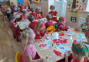 Dzieci wykonują pracę plastyczną przy stolikach "Czerwone jabłuszko".