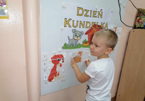 Chłopiec układa na tablicy obrazek z pieskiem.
