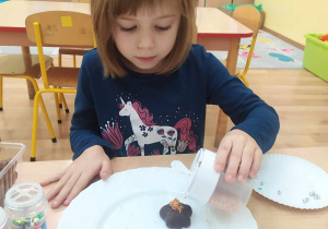 Dziewczynka ozdabia pierniczki cukrowymi pisakami i kolorową posypką.