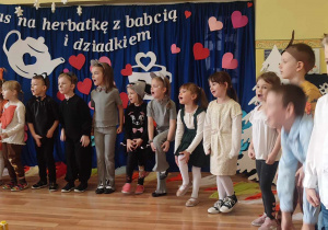 Grupa przedszkolaków w przebraniach leśnych zwierząt podczas improwizacji ruchowej piosenki pt. "Kiedy babcia była mała".