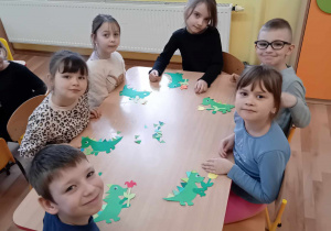 Dzieci przy stoliku wykonują pracę plastyczną - postać programu dinozaura Dinka.