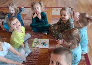 Mała grupa dzieci ułożyła wiosenne puzzle na dywanie.