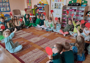 Zabawa "Prawda - fałsz" - dzieci siedzą na dywanie i podnoszą czerwone koła.