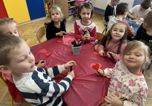 Dzieci przy stolikach wykonują plastyczną - serduszka.