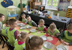 Starszaki przygotowują pizzę do włożenia do foremki.