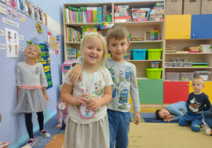 Chłopiec z dziewczynką stoją w parze. Dziewczynka ma medal z napisem "Dzień Dziewczynek".