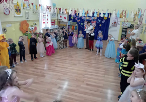 Dzieci na balu stoją w okręgu i ilustrują ruchowo piosenkę pt. A ram sam sam sam.