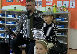 Jedna dziewczynka trzyma klaps a druga kadr filmowy.