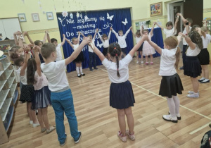 Dzieci tworzą koło, trzymając się za ręce uniesione w górze podczas tańca Poloneza.