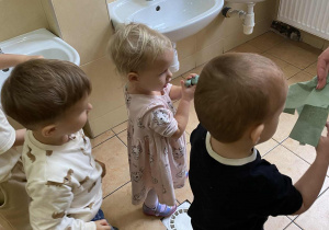 Dwóch chłopców i dziewczynka wycierają ręce papierowymi ręcznikami