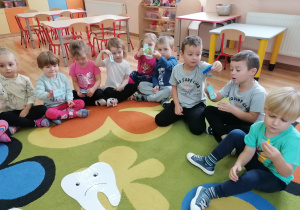 Dzieci trzymają obrazki z produktami zdrowymi i niezdrowymi dla zębów.