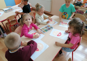 Dzieci rysują kredkami elementy twarzy.