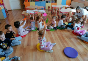 Dzieci w parach przekazują sobie koła uczestnicząc w zabawie ,,Podaj kropkę"