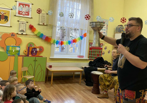 Pan Michał trzyma w ręku aluminiową darbukę. Opisuje jej wygląd, pochodzenie i sposób grania na tym instrumencie.