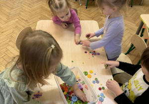 Dzieci tworzą z guzików obrazki.