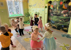 Zdjęcie przedstawia grupę dzieci. Dzieci tańczą w parach do muzyki rozrywkowej.