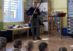 Współprowadzący koncert gra na fagocie. Dzieci słuchają gry.