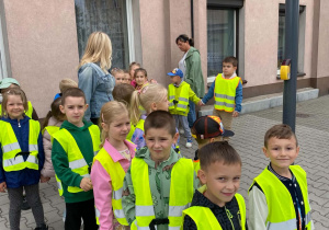 Dzieci stoją przed przejściem z sygnalizacją świetlną, oczekują na zielone światło.