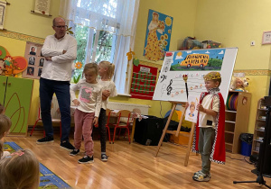Na zdjęciu widzimy Pana Maćka z dwiema dziewczynkami - wszyscy pozują jako modele na wybiegu. Obok nich stoi chłopiec w przebraniu króla..