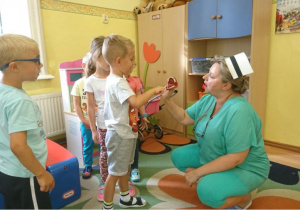 Pani pielęgniarka prezentuje dzieciom model sztucznej szczęki.