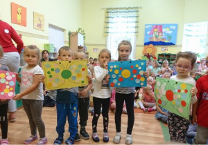 Dzieci prezentują 4 grupowe prace plastyczne - motyle w kolorowe kropki.