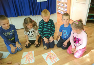 4 dzieci prezentuje ułożone obrazki z części przedstawiające rękę z bakteriami i wirusami.